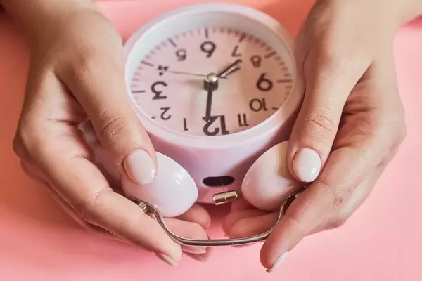 Female checking a time. Woman hands taking an alarm clock.jpg