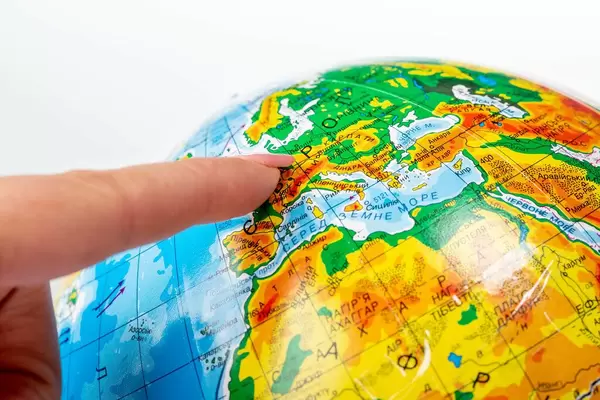Female finger pointing to Europe on the globe