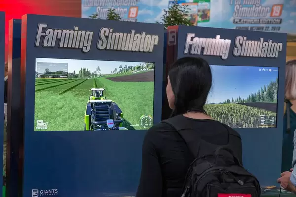 Female games fair visitor plays Farming Simulator by GIANTS Software at Gamescom