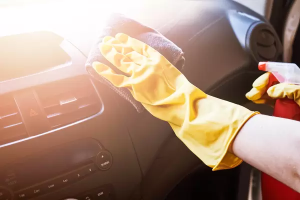Female hand cleaning car interior with microfiber wipe and chemical cleaning spray