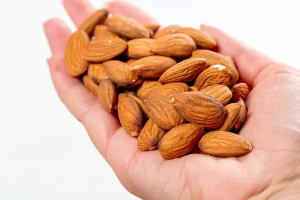 Female hand full of almonds nuts on white background (Flip 2019)