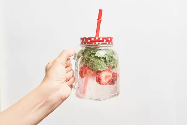 Female hand holding a jar of cold summer fruit cocktail