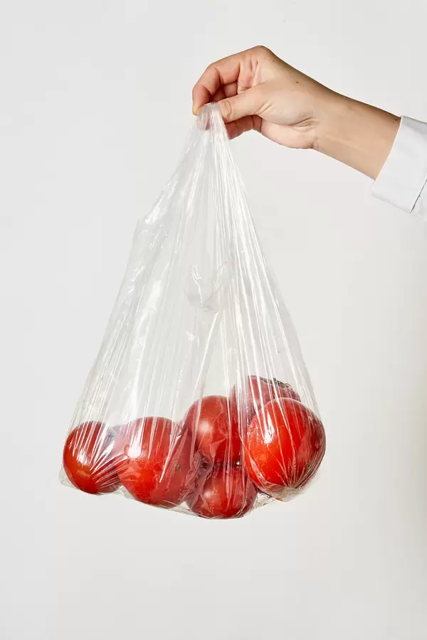 Female hand holding a transparent bag with tomatoes