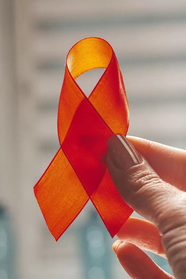 Female hand holding red ribbon on city background (Flip 2019)