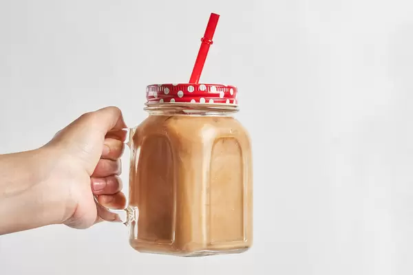 Female hand holds a glass of iced coffee drink