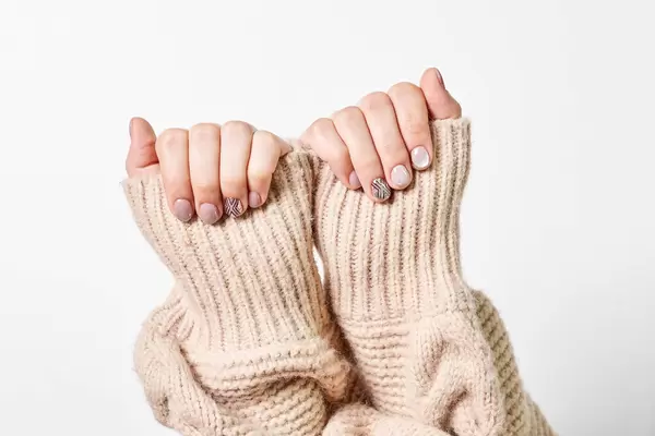 Female hand in a knitted sweater with trendy beautiful manicure