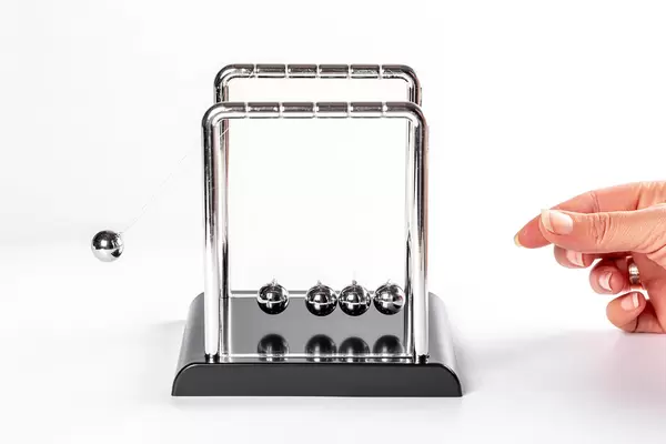 Female hand launching balls of newton's cradle