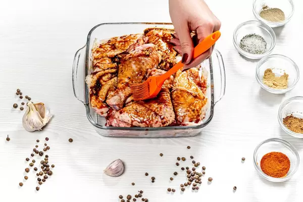 Female hand spreads pieces of chicken marinade. Top view (Flip 2019)