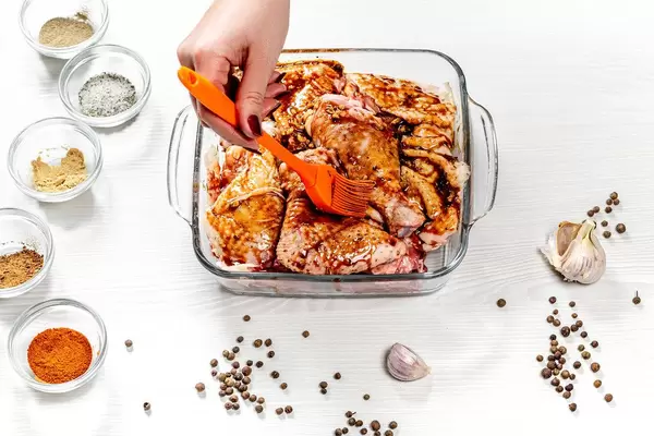 Female hand spreads pieces of chicken marinade. Top view
