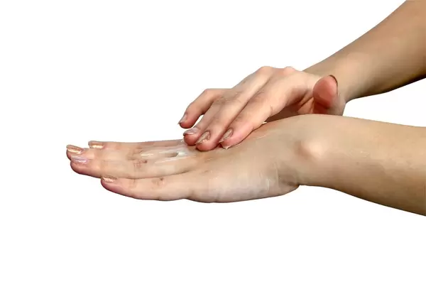 Female hands applying hand cream isolated on white