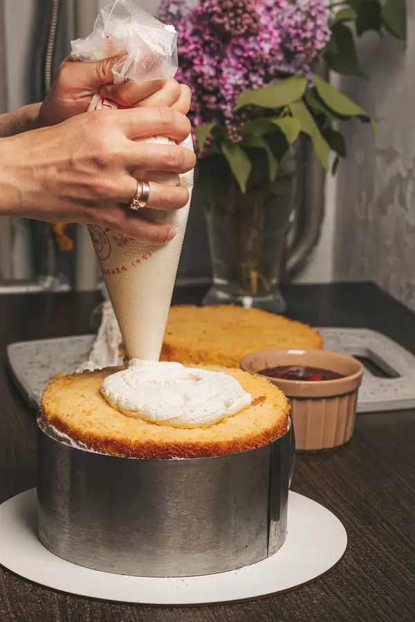 Female hands from a pastry bag squeeze white cream onto a biscuit