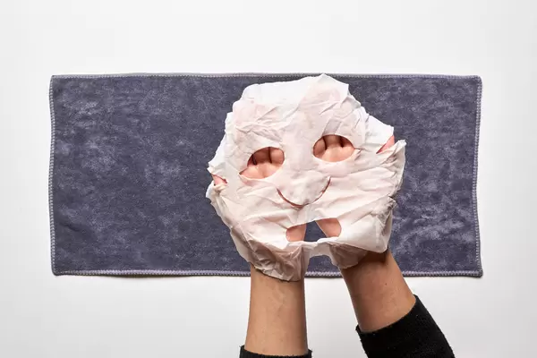 Female hands hold a fabric mask for facial skin
