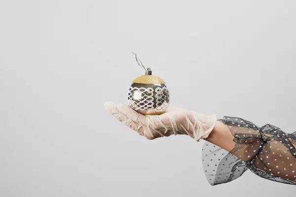 Female hands in medical gloves holding a big Christmas tree toy against the white background