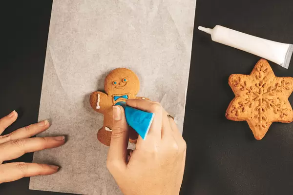 Female hands paint christmas gingerbread cookies