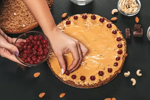 Female hands put alcoholized pitted cherry on cake cream (Flip 2019)