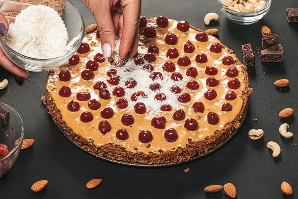 Female hands sprinkle coconut shavings on the cake (Flip 2019)