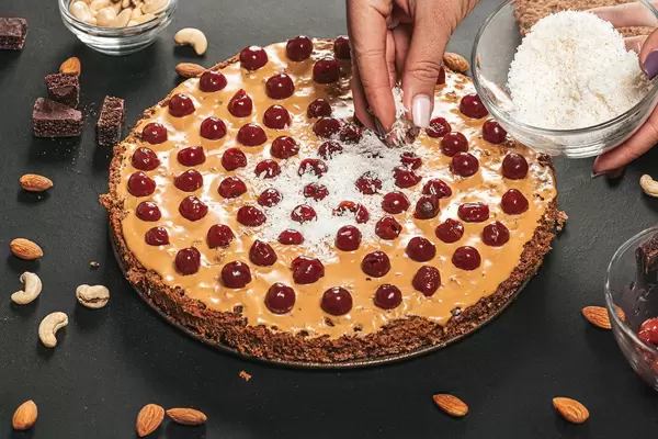 Female hands sprinkle coconut shavings on the cake