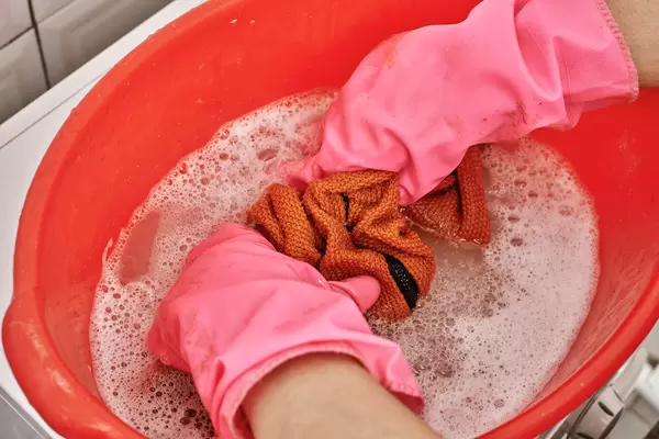 Female hands washing color clothes in washbasin