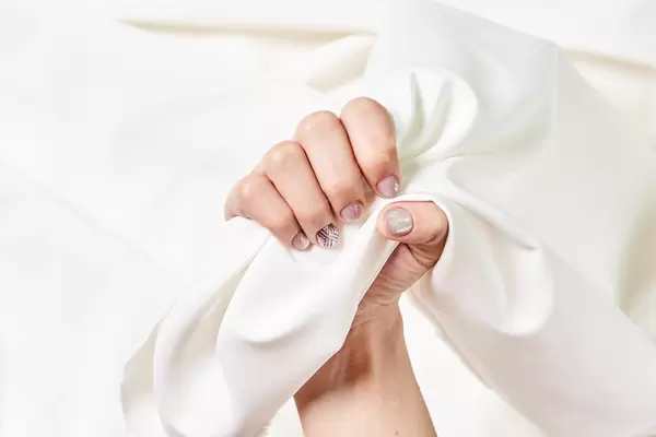 Female hands with beautifully manicured nails on silk fabric