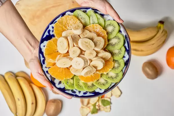 Female holds a plate with sliced tropical fruits set