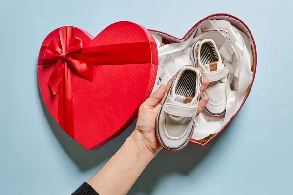 Female taking baby's shoes from gift box
