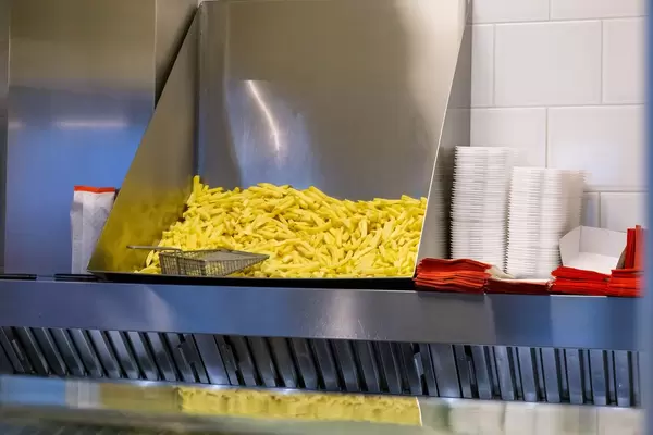 Fertige Pommes Frites in Restaurantküche neben Pappschalen bereit zum Verkauf