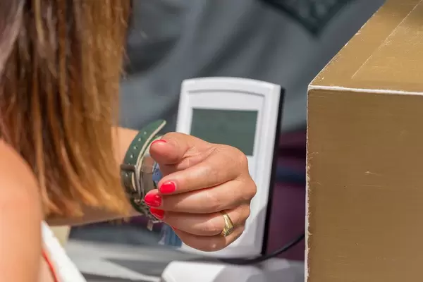 Festival visitor scans her rechargeable money bracelet at terminal to pays cashlessly