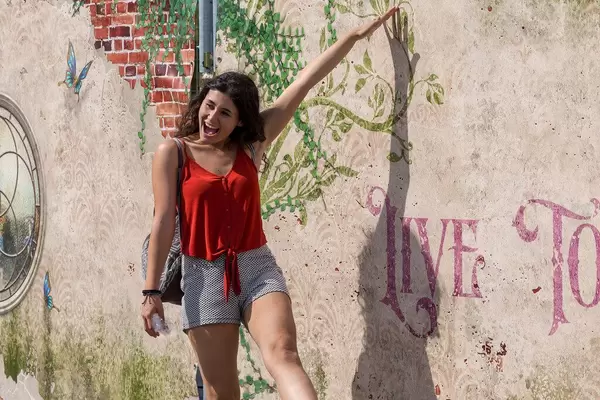 Festivalbesucherin posiert für Foto vor kunstvoller Wand am Tomorrowland Festival 2019 in Belgien