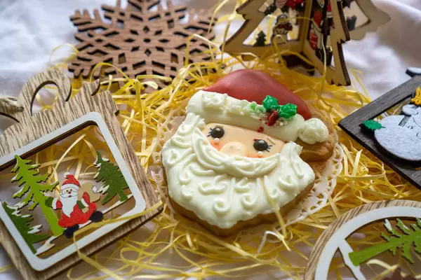 Festive Background Wooden Santa Claus Christmas Decoration next to a Gingerbread Cookie in Santa Claus Form with white and red Icing