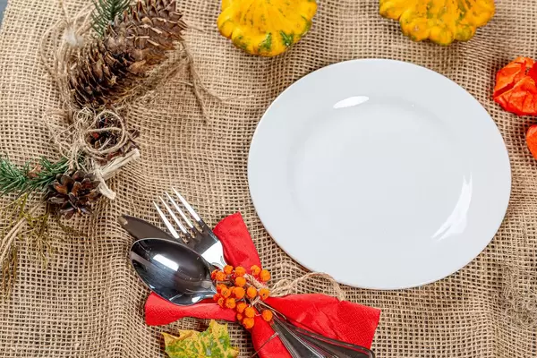 Festliches Gedeck mit leerem Teller und herbstlicher Umrandung auf einem Leinentuch