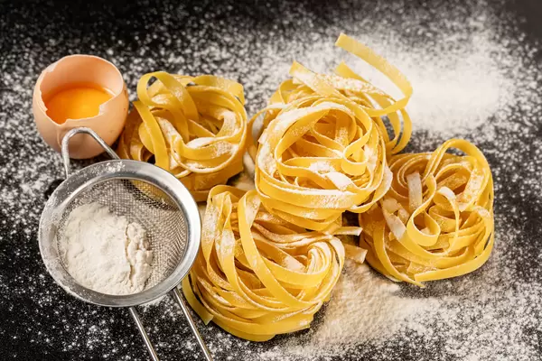 Fettuccine italian pasta on a black background with sprinkled flour