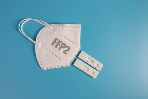 FFP2 medical face mask with Covid-19 antigen test on blue background