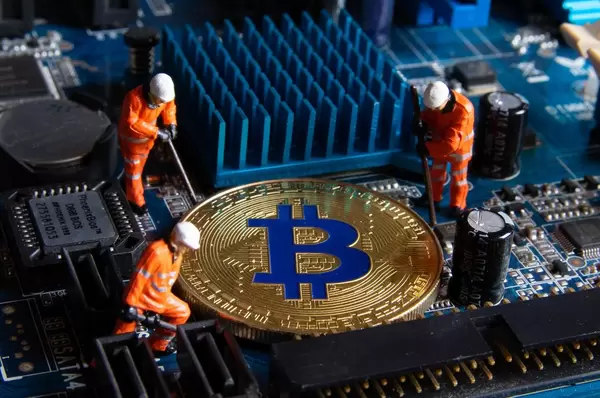 Figures working on a golden Bitcoin