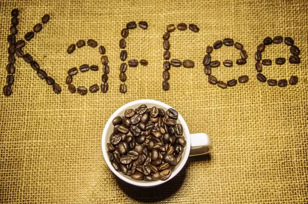 Filled Coffee Cup with Kaffee sign in the Background