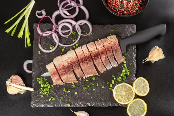 Fillet of lightly salted herring with spices, onion, garlic and lemon, top view