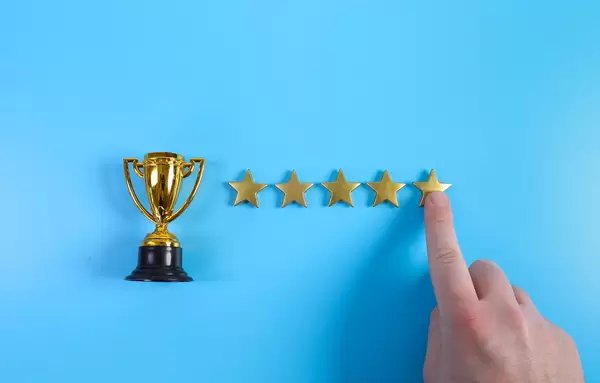 Finger pointing at golden star on blue background