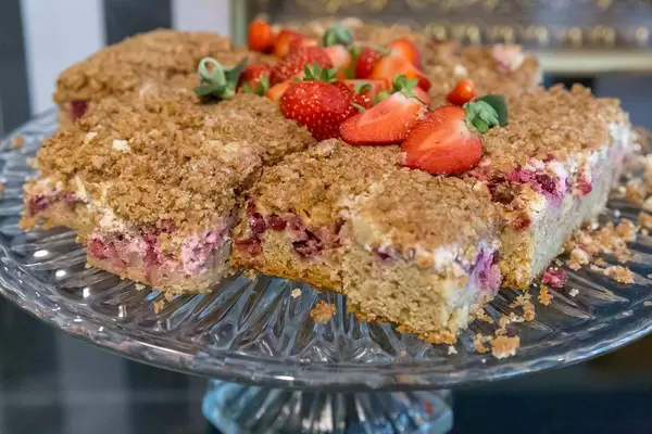 Finnischer Obstkuchen, in Stücke geschnitten und mit Erdbeeren dekoriert, auf einem Kuchentablett