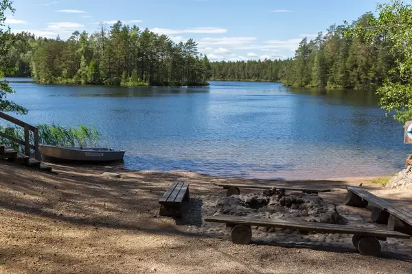 Fireplace made of stones with simple wooden benches on the island Kelvenne, at Lake Päijänne in Finland, next to a rowing boat