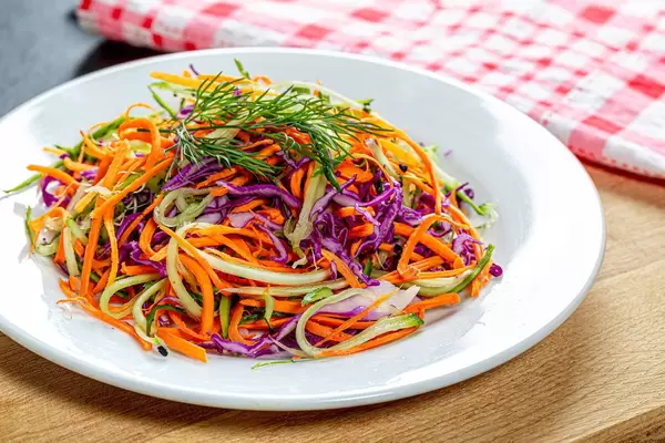 Firscher Salat mit Karotten, Gurken und Rotkraut auf einem weißen Teller