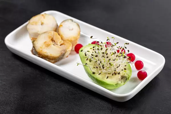 Fisch in Scheiben geschnitten, mit Avocado, Microgreens Zwiebel-Keimsprossen und Preiselbeeren