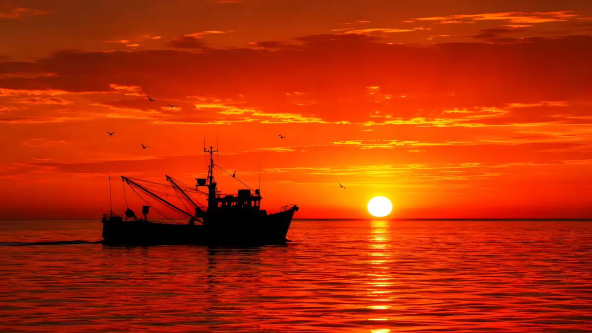Fischerboot als Silhouette vor glutrotem Sonnenuntergang