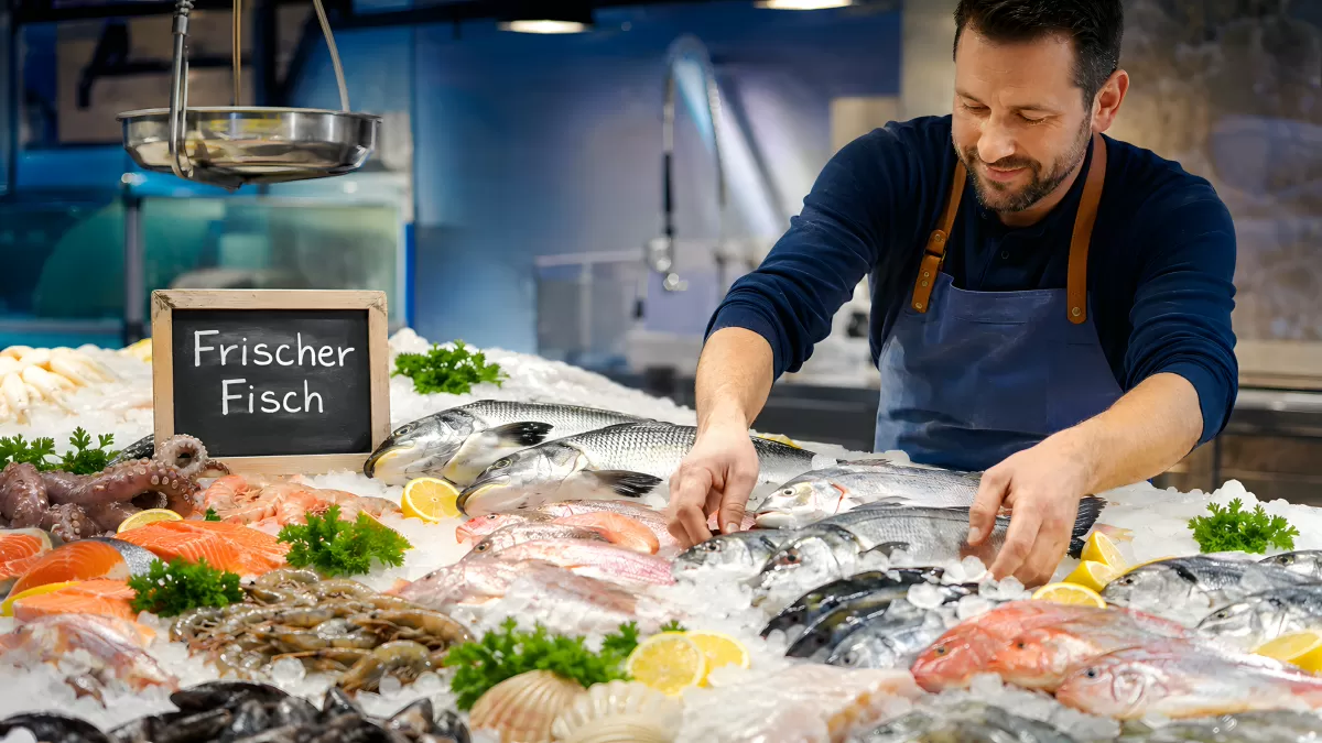 Fischhändler arrangiert frischen Fisch auf Eis im Markt