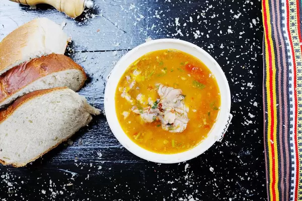 Fischsuppe mit hausgemachtem Brot serviert. Aufnahme von oben mit schwarzem Hintergrund