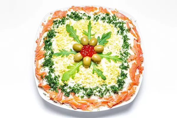 Fish and vegetable salad decorated with fresh herbs, olives and caviar. Top view