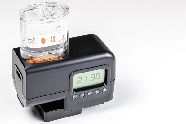 Fish feeder for aquarium with food on a white background