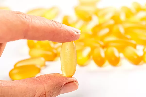 Fish oil capsule in hand, health care and medical concept