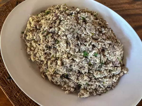 Fish salad with chives on white plate on wooden table
