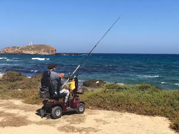 Fit im Alter: Senior angelt im Elektromobil am Strand von Naxos, Griechenland