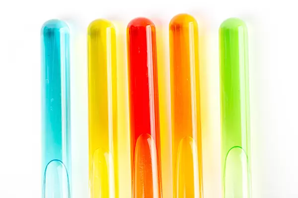 Five test tubes filled with colored liquids on white