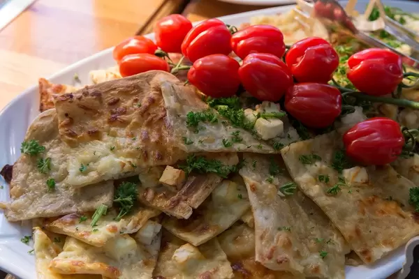 Flammkuchen mit Apfelmus und Fete-Käse, gestapelt auf einem weißen Teller